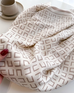 Detailopname van een zachte zijden sjaal met vintage geometrische patronen en beige basiskleur