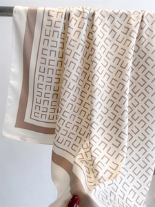 Detail van zijden sjaal met beige geometrische patronen en bruine randafwerking