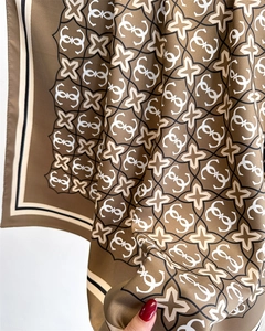 Dettaglio ravvicinato della sciarpa in seta kaki con stelle geometriche e motivi logo