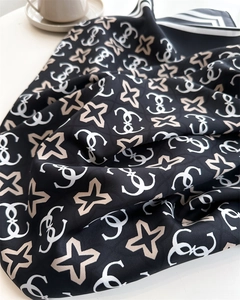 Dettaglio di foulard in seta con motivi a stella e bordi a righe con tazza da caffè