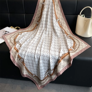 Detailed texture of silk scarf with chain print and logo motif on leather surface