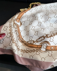 Detail of luxury silk scarf showing golden chain patterns and fine twill fabric texture