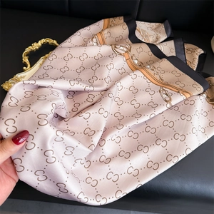Detail of luxury silk scarf showing pink satin fabric with interlocking chain patterns