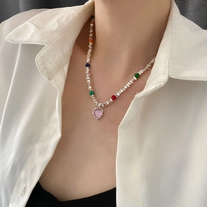 Collier à cœur perlé coloré avec perles carrées argentées sur une chemise blanche
