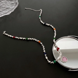 Collier à pendentif coeur coloré avec chaîne argentée et perles arc-en-ciel sur fond noir