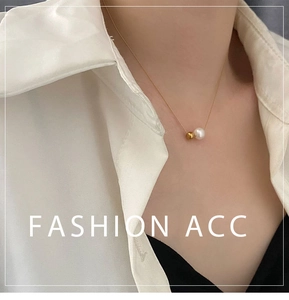 Détail d'un collier doré minimaliste avec perle blanche ronde et bille dorée sur modèle