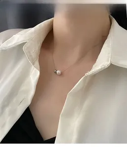 Détail d'un collier minimaliste en acier titane avec perle et pendentif bille en argent
