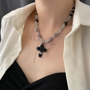 Collier croix gothique avec gravures de roses et perles violettes porté par un mannequin