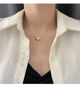 Détail du pendentif perle et bille grise sur une fine chaîne en acier titane