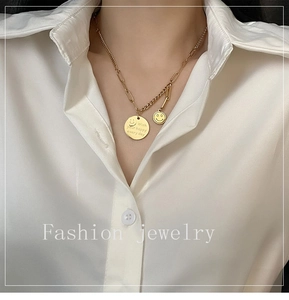Detail of gold smiling face pendant and engraved daily wish message on layered chain