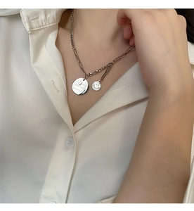 Macro detail of silver smiley face pendants on mixed paperclip chain necklace for women