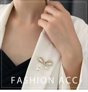 Detail of bow brooch with white pearls on white suit lapel for elegant fashion look