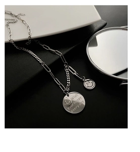 Detail of silver smiley face necklace with rectangular links and engraved round pendant