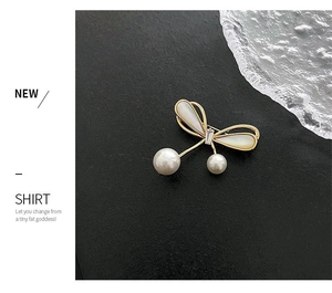 Detailed view of elegant golden bow brooch with pearls and white shell-style wings