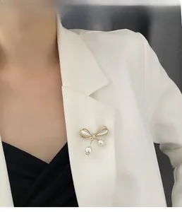 Detail of bow-shaped brooch with pearls pinned on a white blazer lapel