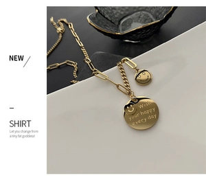 Macro shot of gold-plated necklace with double smiley face pendants and engraved message