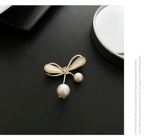 Detailed macro view of bowknot brooch with white mother of pearl and hanging pearls