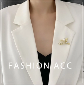 Golden branch brooch with pearls on white blazer lapel showing elegant fashion style