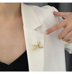 Elegant gold leaf brooch with white pearls pinned to a white blazer lapel