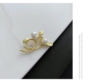 Detailed view of elegant gold leaf brooch featuring white pearls and crystal inlay detail