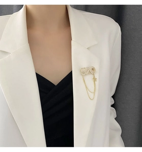 Détail d'une broche chaîne 520 avec strass scintillants sur un blazer blanc