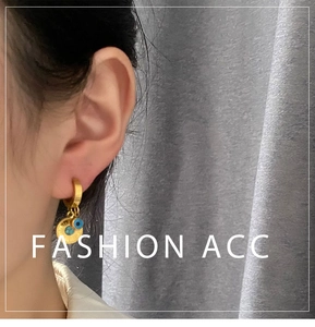 Detail of gold hoop earrings with etched disc and blue evil eye bead on model
