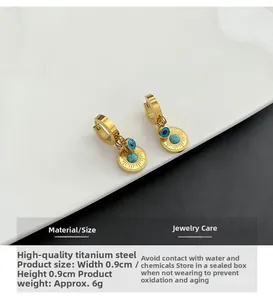 Detailed view of gold evil eye and sunburst earrings made of titanium steel