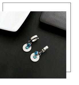Detail of silver drop earrings with evil eye beads and turquoise-style discs