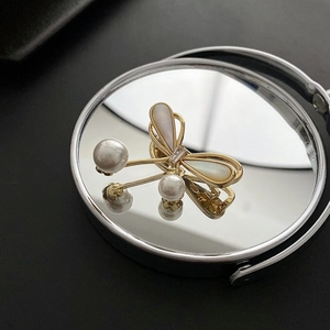 Elegant gold butterfly brooch with white pearls and mother of pearl on a reflective surface