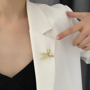 Elegant gold leaf brooch with white drop pearls and crystal on a white suit lapel