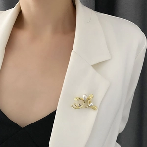 Elegant gold branch brooch with white drop pearls on a white blazer lapel for women