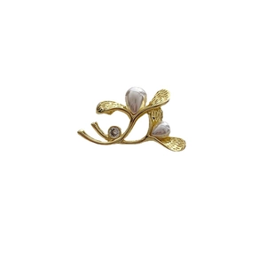 Elegant gold branch brooch featuring two white pearls and a sparkling crystal accent