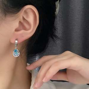 Silver evil eye drop earring with sunburst engraving and turquoise stone on model