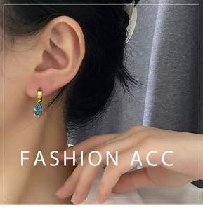 Gros plan de boucles d'oreilles dorées Evil Eye portées par un mannequin de luxe