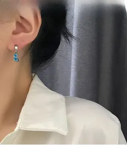 Gros plan de boucles d'oreilles œil porte-bonheur en argent portées par un mannequin chic