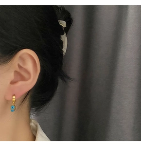 Gros plan de boucles d'oreilles dorées avec perles œil bleu sur modèle