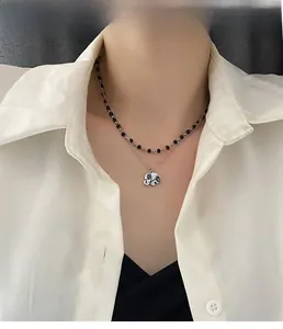 Close-up of double-layered necklace with black beads and elephant pendant on a model