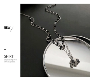 Macro detail of a silver-tone double-layered necklace with black beads and a round pendant