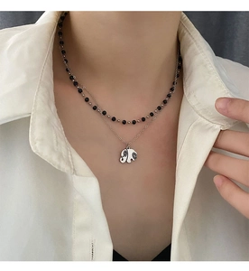 Detail of layered double necklace featuring black beaded chain and elephant pendant