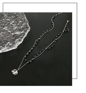 Macro view of double-layered titanium necklace with polished elephant charm and black beads