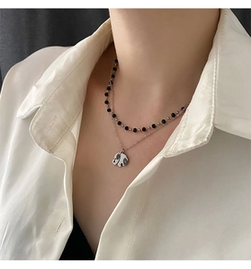 Close-up of double-layered titanium steel necklace with elephant pendant on white shirt