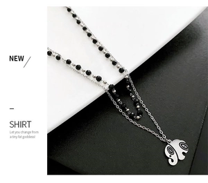 Detail of double-layer necklace with a vintage elephant pendant and black beads