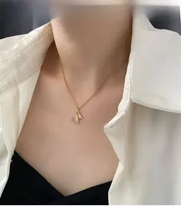 Dettaglio della collana con ciondolo a farfalla dorata e cristallo cangiante sulla modella