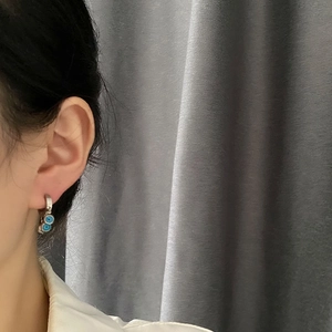 Boucles d'oreilles œil maléfique en acier titane portées par un mannequin sur l'oreille