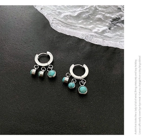 Orecchini a cerchio in argento con tre perline turchesi azzurre su sfondo scuro testurizzato