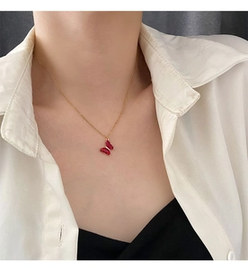 Dettaglio di una catena dorata con ciondolo a farfalla in cristallo rosso su una modella