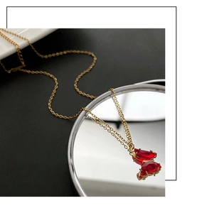 Dettaglio della collana a farfalla dorata con pendenti in cristallo rosso su uno specchio