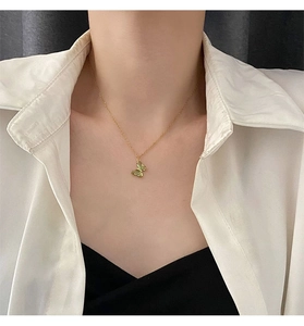 Dettaglio di una collana placcata oro con ciondolo a farfalla in cristallo verde vivace