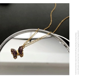 Vista macro della collana con ciondolo a farfalla con cristalli viola e finitura dorata