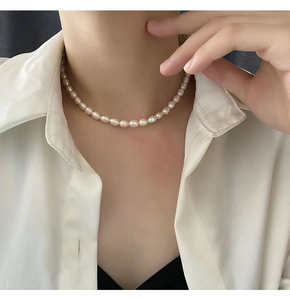 Close-up of baroque freshwater pearl necklace worn on neck over a white shirt